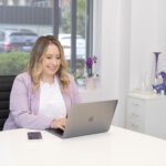 Marketing Consultant Sarah Christie sitting at desk working on laptop