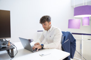 Justin Cuzzocrea, Marketing Co-ordinator sitting at desk working on laptop